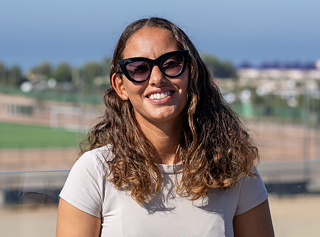  مريم الجردوم في مقهى، على بعد حوالي 500 مترًا من مكان شهير لركوب الأمواج، وهو ما يسمى بنقطة الاستراحة: صخرة الشيطان.