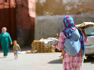 Eine Frau mit Kopftuch läuft einer anderen Frau mit Kind entgegen.