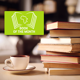 ein Bücherstapel rechts im Bild vor einer Bücherwand, links daneben eine dampfende Kaffeetasse