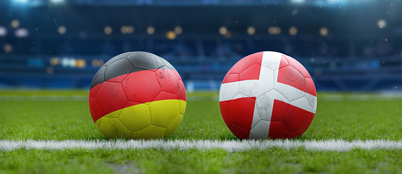 two soccer balls next to each other on a lawn in a stadium one depicting Germany's flag and the Swiss flag