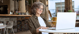 Middle ages woman sitting at table with latop