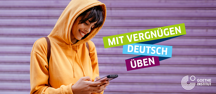 Eine junge Frau blickt lächelnd auf ihr Handy