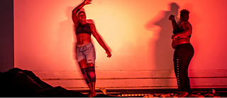 Zwei Frauen auf einer dunklen Bühne mit rotem Licht