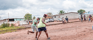 Zwei Personen rennen auf einem staubigen Feld.