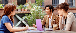 Three people talking at a desk table