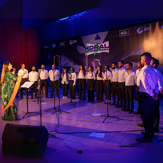 Ein einheitlich gekleideter Chor singend auf der Bühne 