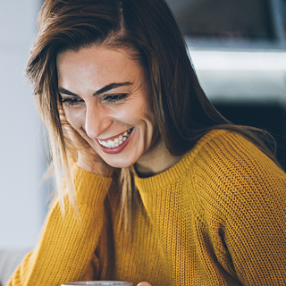 Woman smiling during an online German conversation group with Goethe-Institut USA, practicing speaking skills with fellow learners.