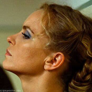 Close up af skuespilleren Nina Hoss, der spiller hovedkarakteren Barbara i Christian Petzold spillefilm Barbara fra 2012. Hun bærer tung make up og ser lidende til siden. 