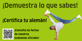 Ein junger Mann mit Wollmütze macht Handstand und lächelt in die Kamera