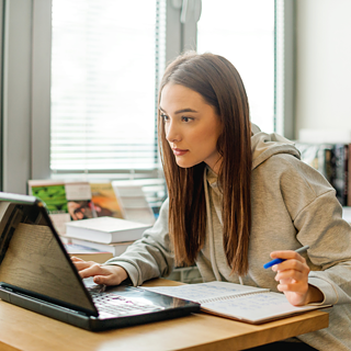 Eine junge Frau lernt intensiv und konzentriert an ihrem Laptop und nutzt Online-Lernen zur schnellen Wissensvertiefung.