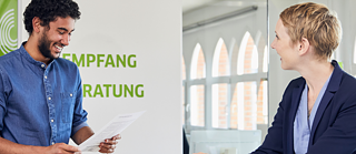 Two people in conversation at the Goethe-Institut, one holding a document and smiling.