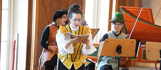 Une actrice joue avec émotion devant un groupe de musiciens, tous habillés en fonction de la pièce du joueur de flûte.