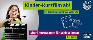 Kind mit Filmklappe in der Hand, lachend