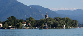Blick auf den Chiemsee. Segelboote im Vordergrund, Bergpanorama im Hintergrund.