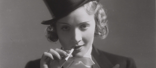 Filmstill fra Marokko med Marlene Dietrich i buksedragt, hat og cigaret.