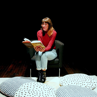 In der Bibliothek hören Kinder einer Frau beim Geschichtenerzählen zu