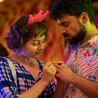 Franky betrachtet die Hände eines Jungen auf einem Jahrmarkt.