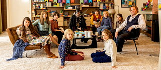 Zehn Personen posieren für ein Foto im Wohnzimmer.