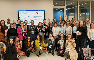 사람들이 대형 스크린 앞에서 함께 서서 사진을 찍으며 웃고 있습니다.