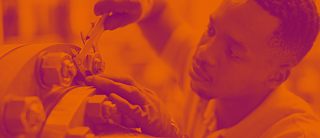 Männliche junge Person misst ein Teil an einer Maschine, trägt Arbeitshandschuhe, Bild in orangen und violetten Farbtönen