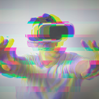 Hombre joven con lentes de realidad virtual y los brazos estirados, la imagen se ve pixelada