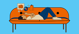 A person is lying on the sofa and is using their mobile phone.