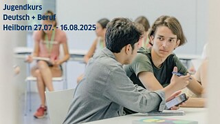 Zwei junge Männer sitzen zusammen in einem Kurs und diskutieren angeregt miteinander