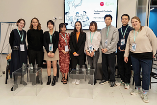 A group of people stand in front of a screen and view the displayed content together.