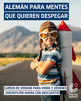 Ein Junge von ca 9 Jahren steht in der Wüste, er hat Sommerkleidung an, eine Pilotenmütze auf und grinst in die Kamera. Auf dem Rücken hat er eine Rakete geschnallt. 