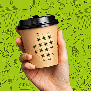 eine Hand hält ein Kaffeebecher, im Hintergund Illustrationen von typisch deutsche Bilder