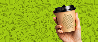 mano sosteniendo un vaso de café sobre fondo con ilustraciones de cosas típicas alemanas