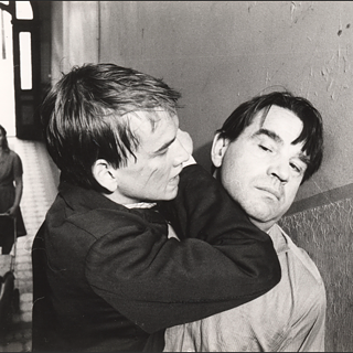 A blond young man and an older dark-haird man fight with each other