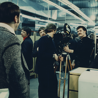 Fassbinder zusammen mit Schauspielern und einer Kamera beim Filmen des Films.