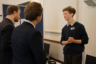 Ein Teilnehmer des Wettbewerbs erklärt den Alumni, was er im Rahmen seines Projekts getan hat.