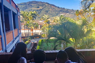 Jugendliche Schüler*innen auf einem Balkon, im Hintergrund tropisches Bergland