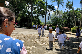 Eine Gruppe kleiner Kinder auf einem Hof, im Hintergrund Palmen