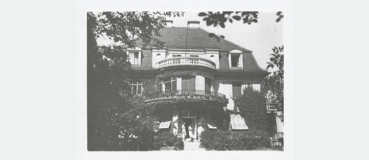 Schwarz-weiß Bild. Haus der Familie Mann an der Poschingerstrasse, Aussenansicht. Vor dem Hause stehen von links: Klaus Mann, Erika Mann, Thomas Mann.