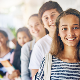 Fünf Jugendliche schauen lachend in die Kamera