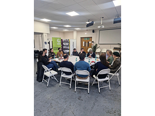 Die Teilnehmer sitzen in einem Konferenzraum an einem Tisch und diskutieren miteinander