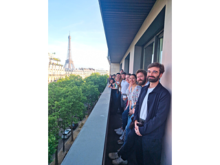 Auf dem Foto sind zwanzig junge Menschen auf dem Balkon des Goethe-Institut Paris zu sehen. Im Hintergrund sieht man den Eiffelturm.