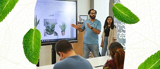 يقف بافلي بجانب لوح ويشرح للحضور أنواع النباتات