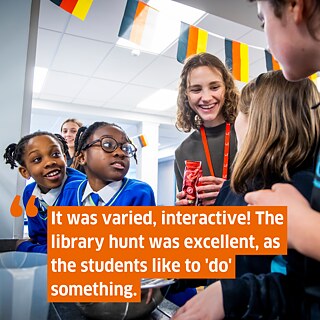 A group of young black pupils around a young German person wearing a staff badge, smiling. Superimposed the following text: It was varied, interactive! The library hunt was excellent, as the students like to 'do' something.