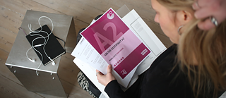 Blick von oben auf eine Deutschlehrerin, die ein Goethe-Zertifikat A2 in der Hand hält.
