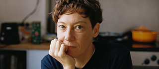 Bild von der Künstlerin Christine Gensheimer wie sie in der Küche sitzt