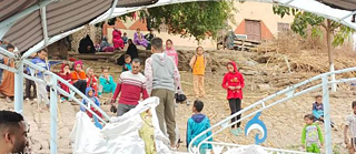 صورة من قارب في نهر النيل تُظهر مجموعة من سكان محافظة قنا، من الأطفال والكبار، وهم يقفون على الشاطئ.