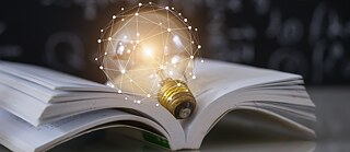 A light bulb sits atop an open book, representing inspiration and learning