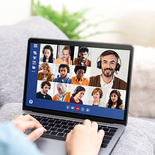 Blick auf einen Bildschirm eines Notebooks, auf dem Personen in einem Online-Meeting zu sehen sind.