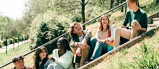 A diverse group of young friends relaxing on a hill, surrounded by nature, sharing laughter and storie