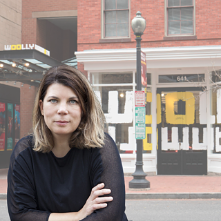 Eine Frau, die in die Kamera blickt, während sie vor dem Woolly Mammoth Theatre steht.