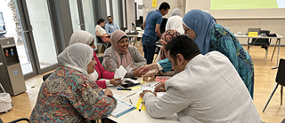 مجموعة من المدرسات تجلسن معًا على طاولة مستديرة خلال ورشة عمل لمشروع مدارس صديقة للبيئة